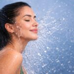 Close-up of a woman rinsing her face with cool water; a visual representation of how cold water can soothe skin, close pores, and improve circulation after a warm shower. Hot Water Showers