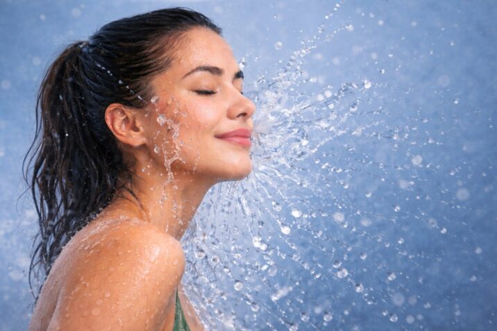 Close-up of a woman rinsing her face with cool water; a visual representation of how cold water can soothe skin, close pores, and improve circulation after a warm shower. Hot Water Showers