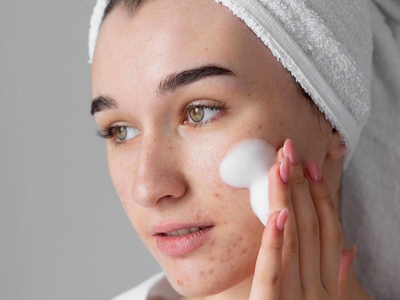 A close-up showing the proper way to apply a gentle foaming wash to breakout-prone skin to avoid irritation.