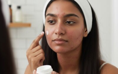 Woman applying face cream to acne-prone skin while looking in a mirror