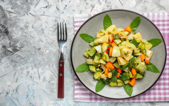Bowl of fresh mixed vegetable salad served on a plate with fork
