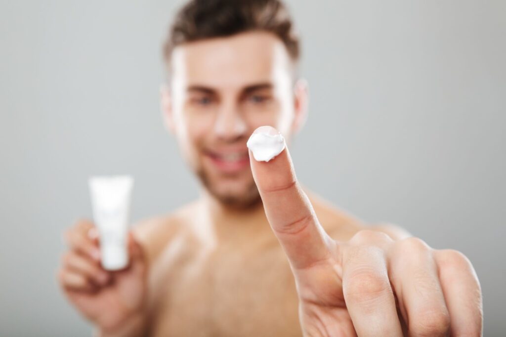 Man holding a small amount of face cream on his fingertip during a skincare routine